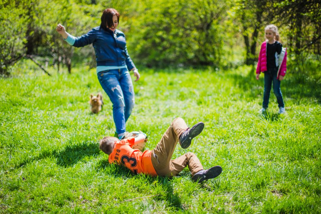 Family enjoying outdoor playtime on a sunny day with a dog in a green park