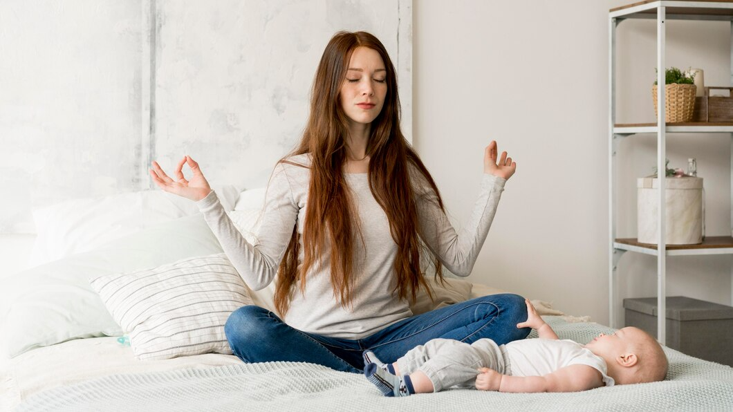 A woman sits on a bed, gently cradling her baby in her arms, both appearing calm and content