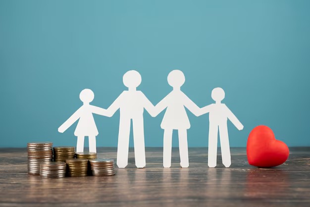 Paper cutout family figures alongside money on a blue table, symbolizing family and financial concepts